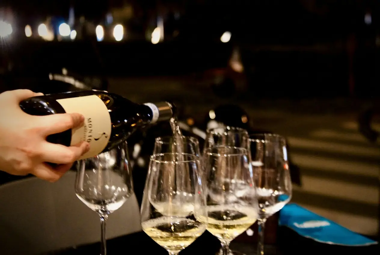 Calici di vino riempiti durante un aperitivo serale a Capolaterra Cafè